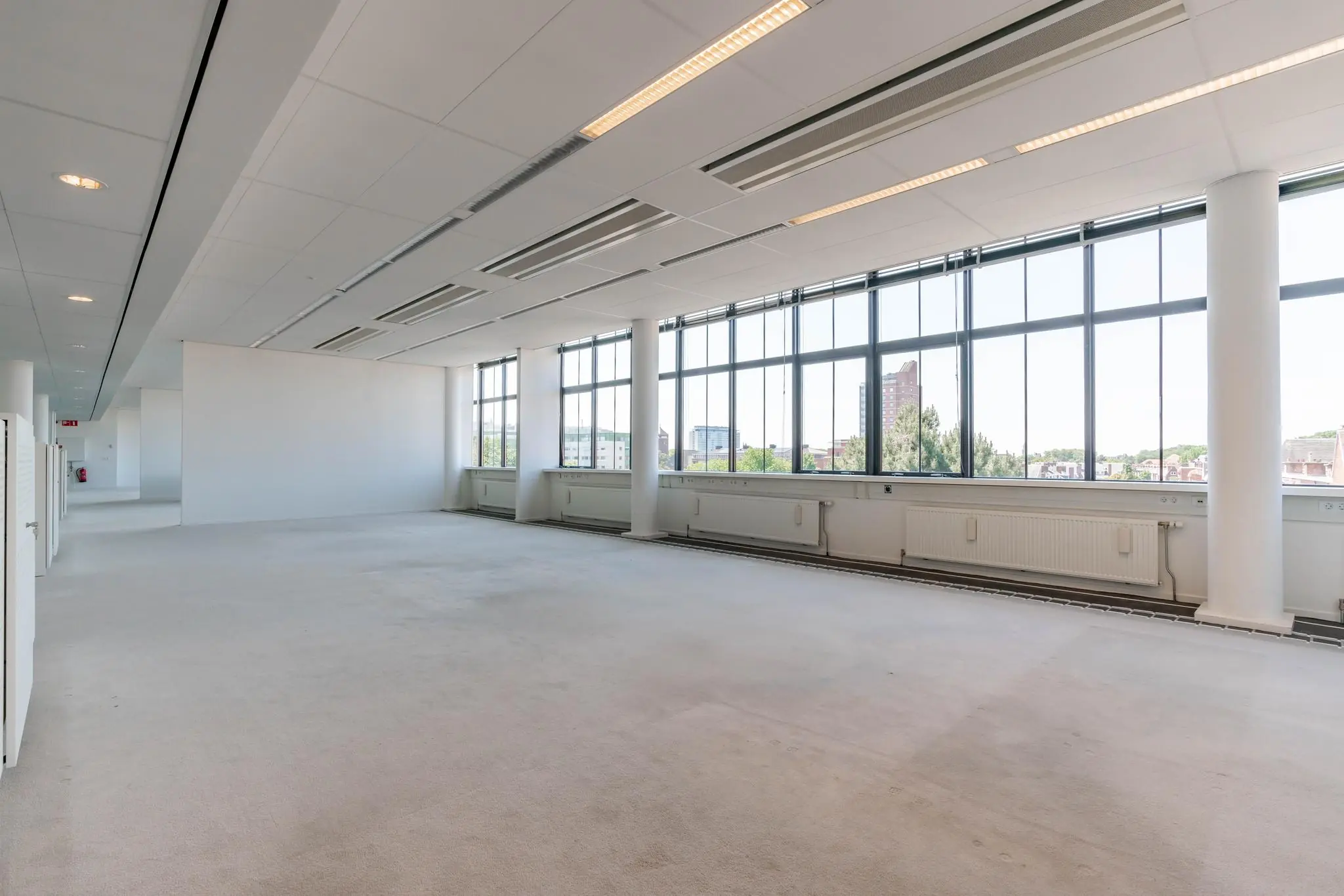 Licht en ruim kantoorinterieur aan de Van Alkemadelaan met grote ramen en uitzicht op de stad.